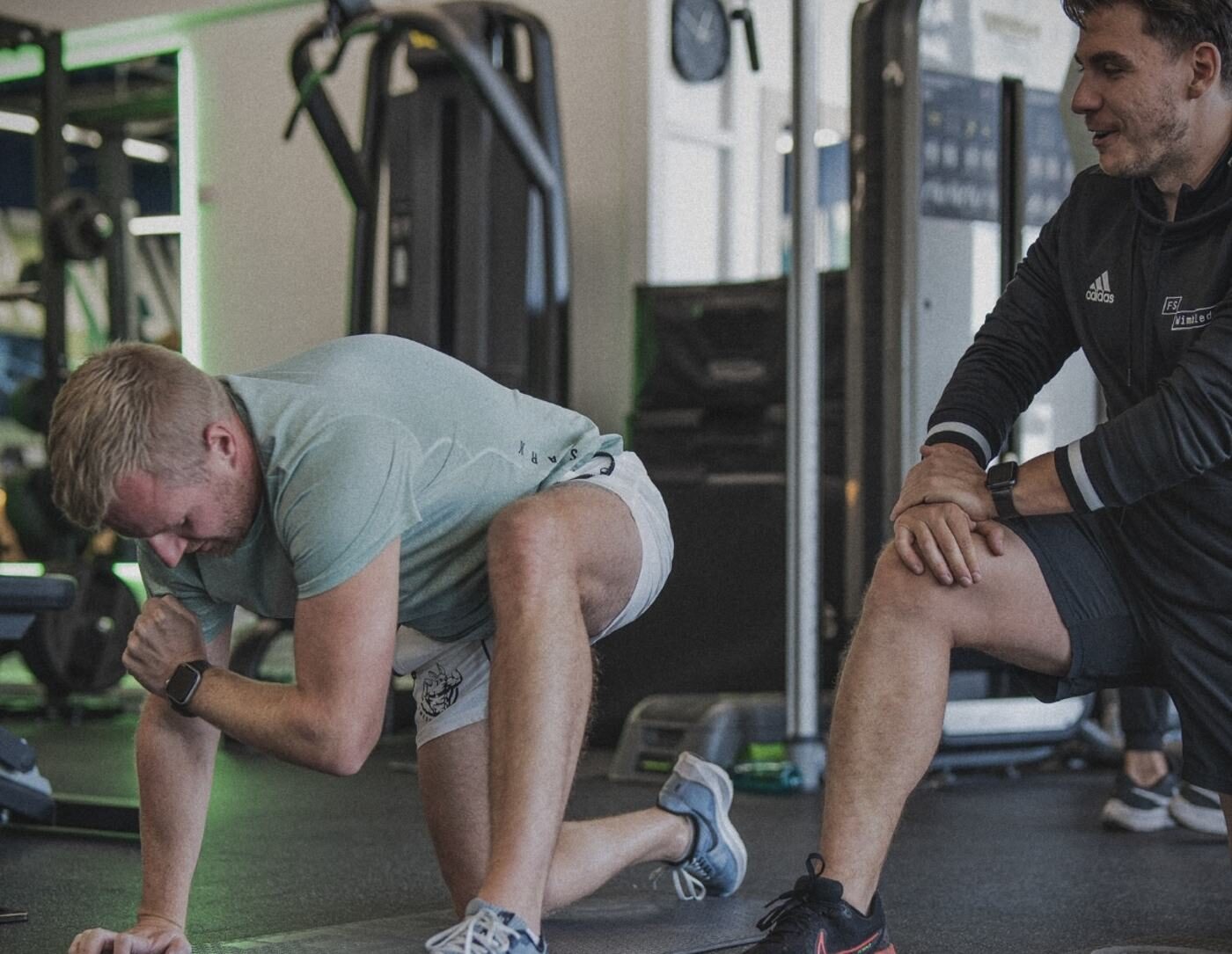 Matt Fossey coaching a client through a hip flexor mobility stretch in the gym